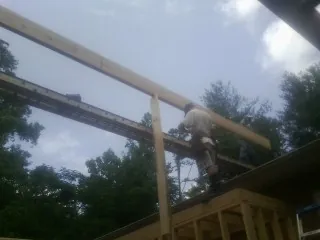 Carpenter setting a ridge beam over a new addition frame — Ice Dam Removal by Roofing Brothers in Butte
