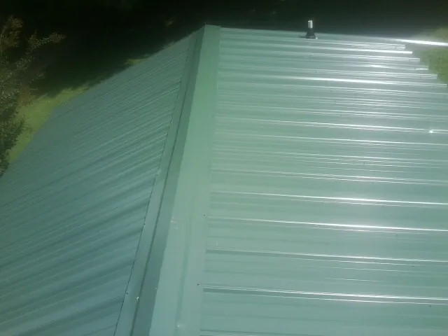 New green metal panels meeting at the ridge of a roof — Flat Roof Repair work by our crew in Butte
