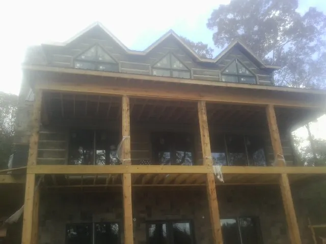 Dormers and porch framing on a large log home under construction — Roof Coating work by our crew in Butte
