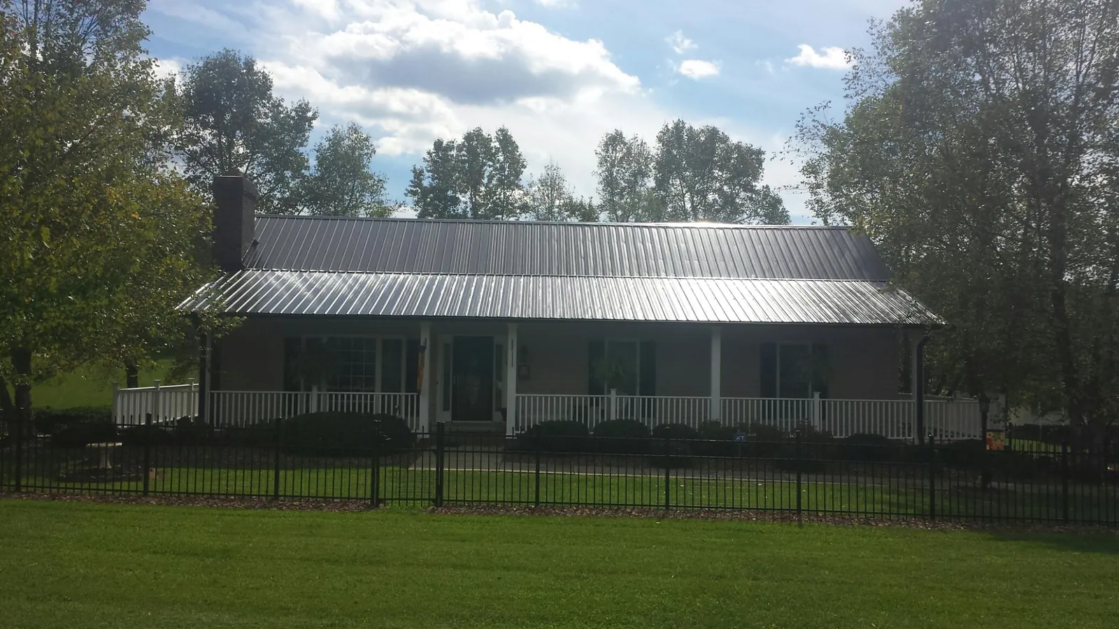 Gray metal roof on a brick ranch with a full width front porch — Gutter Guard Installation work by our crew in Butte