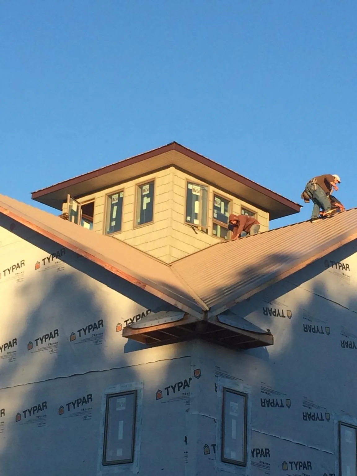Roofers working around a rooftop cupola on a new metal roof at sunset — Roof Waterproofing in Butte by Roofing Brothers